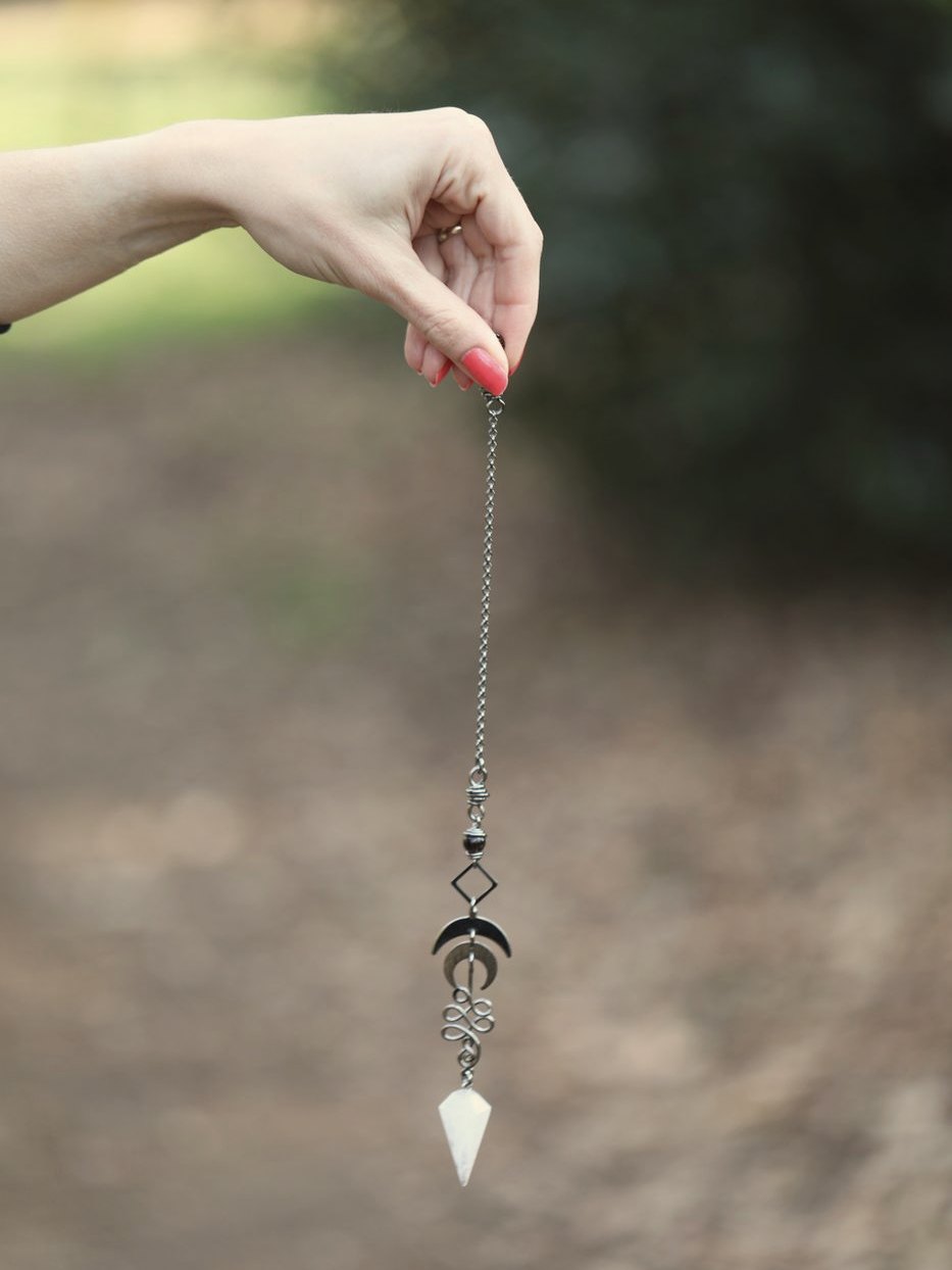A crystal pendulum held still above the ground